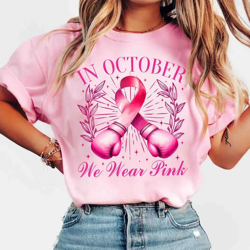 Pink graphic T-shirt with breast cancer ribbon and “In October We Wear Pink” text